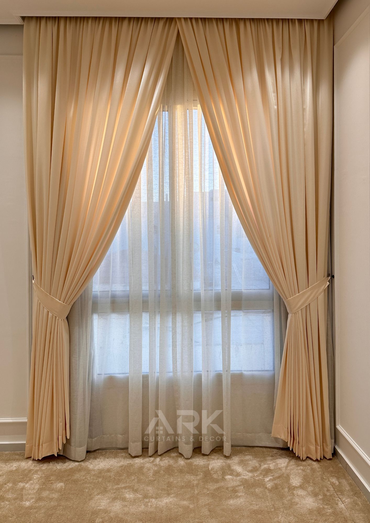Beige tied-back curtains with sheer centre panel and soft lighting