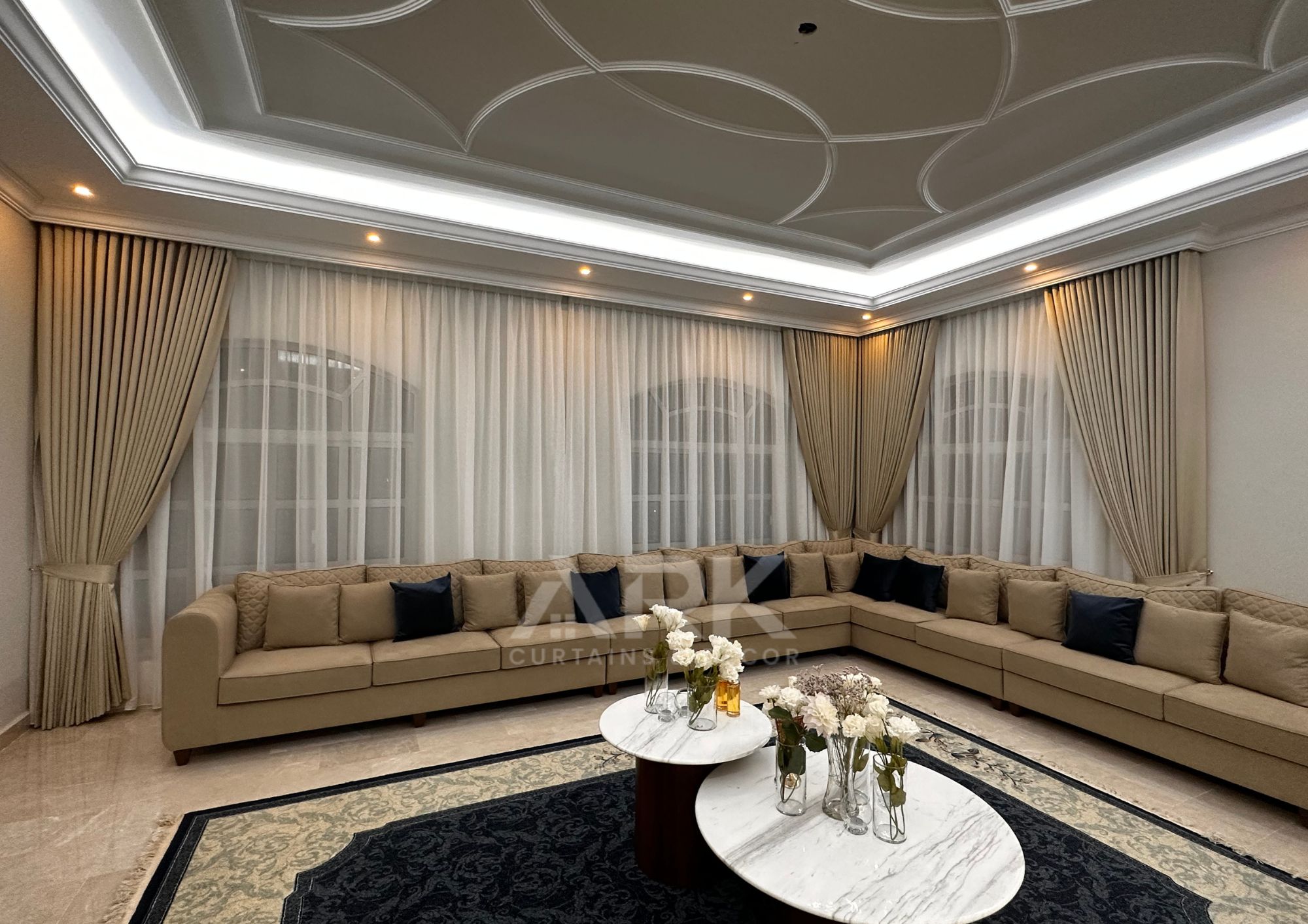 Spacious majlis with layered sheer and blackout curtains, ornate ceiling and marble flooring