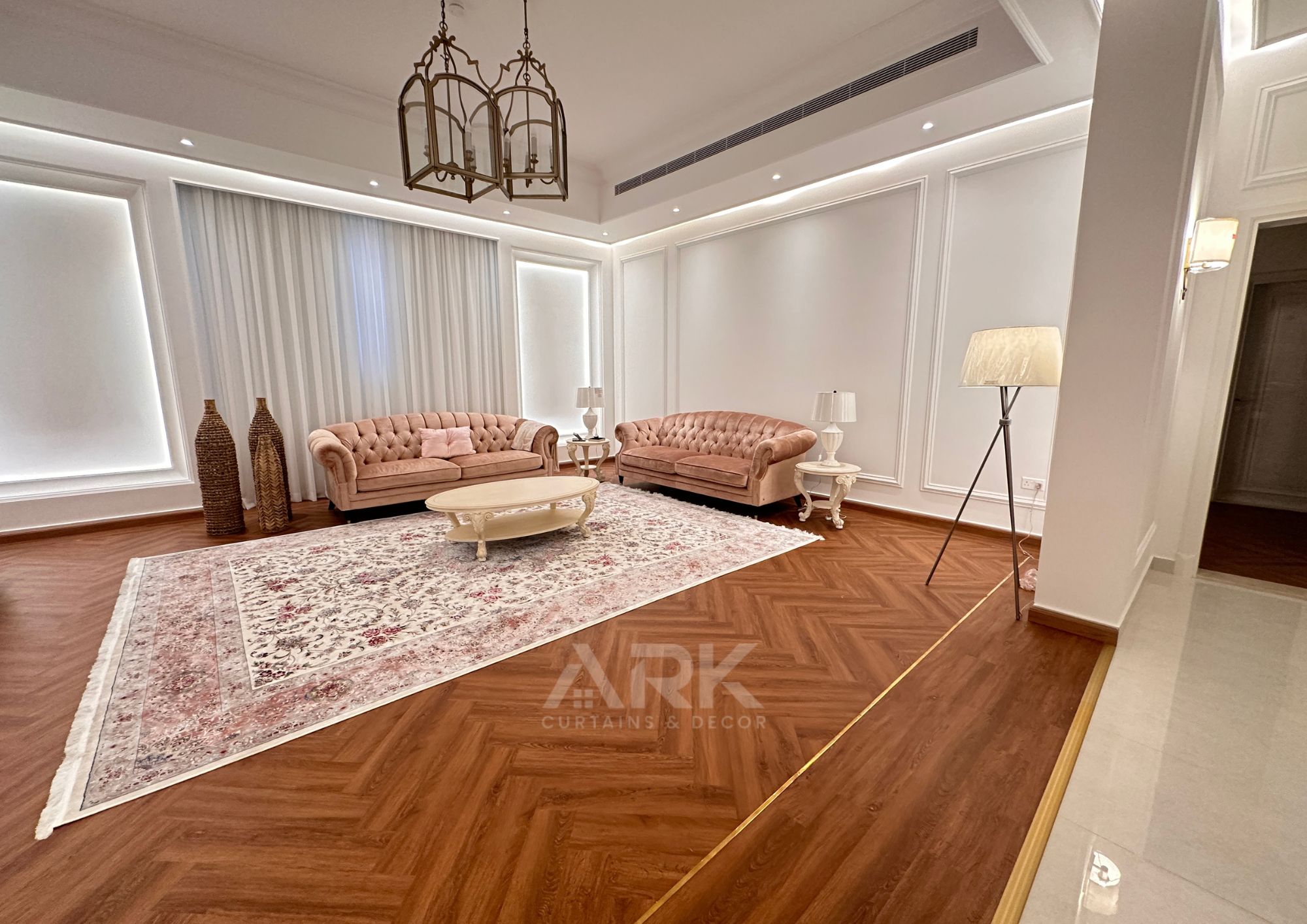 Bright living room with sheer curtains, herringbone wood floor and pink sofas
